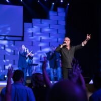 man in black suit singing on stage