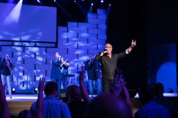 man in black suit singing on stage