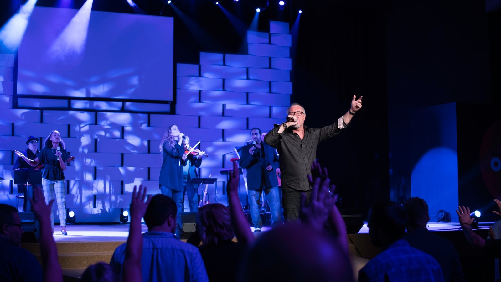 man in black suit singing on stage